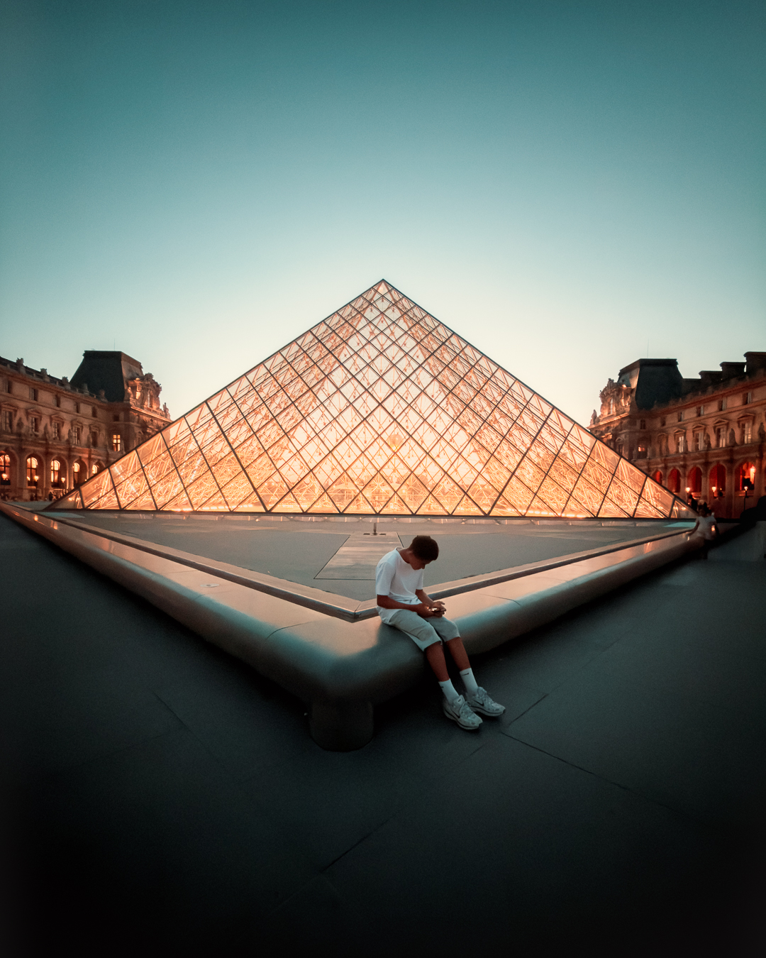 Cole at the Louvre beneath the geometric glass pyramid.